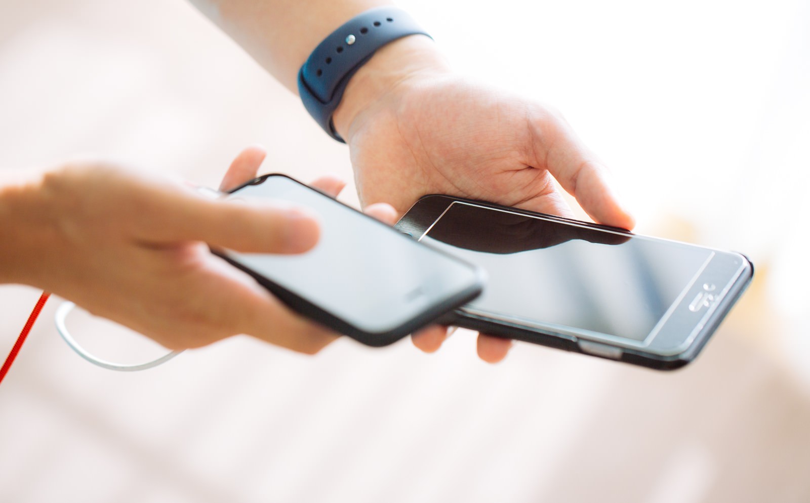 スマートウォッチを付けた腕でスマホを2台持つ
