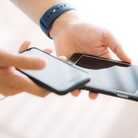 スマートウォッチを付けた腕でスマホ二台持ちの写真
