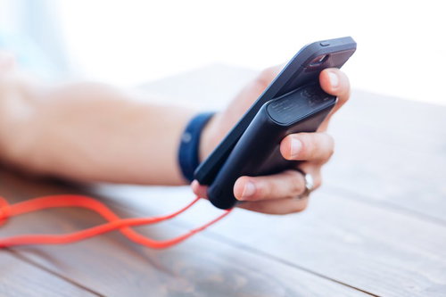 手のひらサイズのモバイルバッテリーとスマートフォン、紅白ボールストラップ