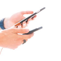 両手にスマホを持ってゲームアプリをプレイする男性の写真