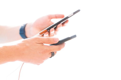 両手にスマホを持ってゲームアプリをプレイする男性