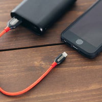 赤いケーブルで接続したモバイルバッテリーでスマホを外出先でも安心充電の写真
