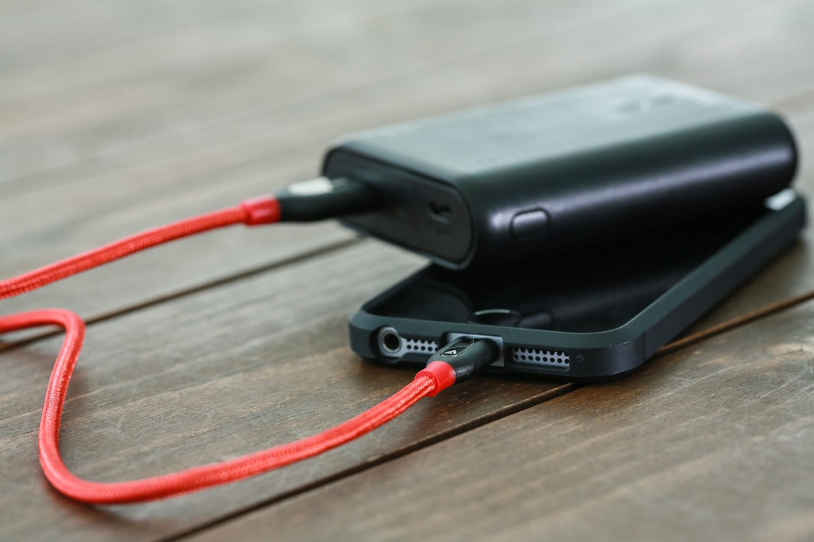 赤いケーブルでモバイルバッテリーからスマホに充電している