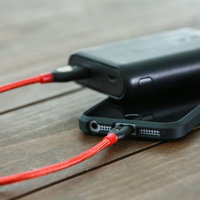 赤いケーブルでスマホに充電するモバイルバッテリーの写真