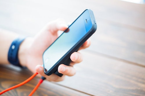 モバイルバッテリーからオレンジのケーブルでチャージしながらスマホを使う