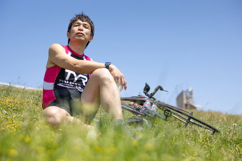 河川敷の芝生で休息するトライアスロン選手