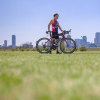 競技用ロードバイクを押しながら歩くトライアスロンの男性選手の写真