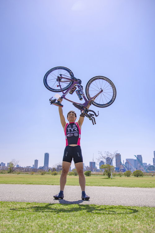 レースを完走して自転車を掲げ記念写真を撮るトライアスリート