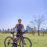 青空の下でロードバイクを持つトライアスロン選手の男性の写真