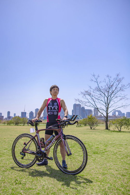 青空の下でロードバイクを持つトライアスロン選手の男性