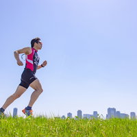 トライアスロン種目「ラン」を草原で走る男性の写真