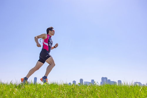 トライアスロン種目「ラン」を草原で走る男性