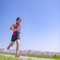 河川敷をランニングするトライアスロンの選手の写真