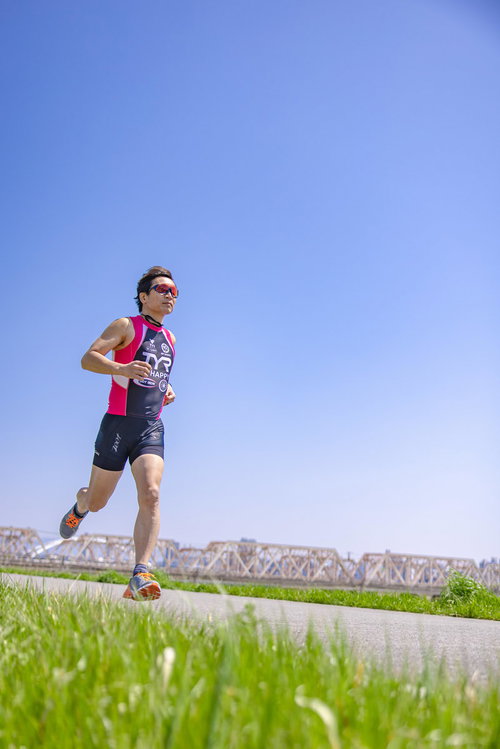河川敷をランニングするトライアスロンの選手