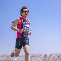 サングラスをかけて走るトライアスリート男性選手の写真