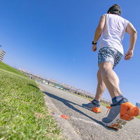 アスファルト道路をダッシュするランニング男性の足元の写真