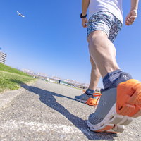 オレンジ色のランニングシューズでアキレス腱を伸ばすアスリートの写真