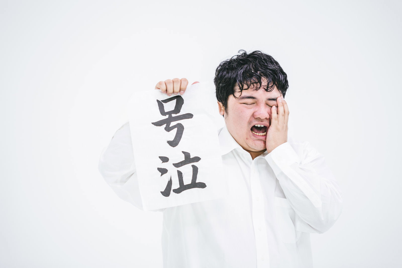 白い背景で号泣している黒髪の男性の表情［モデル：段田隼人］