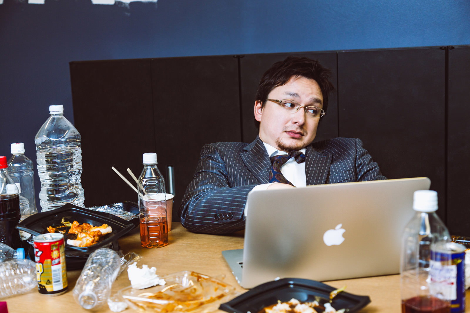 連休中も散らかったデスクでノートパソコンに向かう男性［モデル：Max_Ezaki］