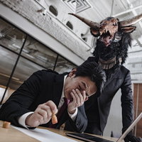 悪魔と契約を結ぶ会社員がスーツで判子を押すの写真