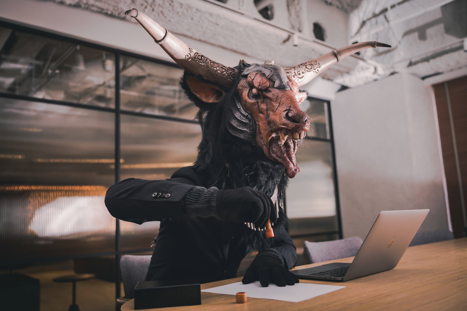 スーツ姿の悪魔が机に向かい書類作業をしている様子