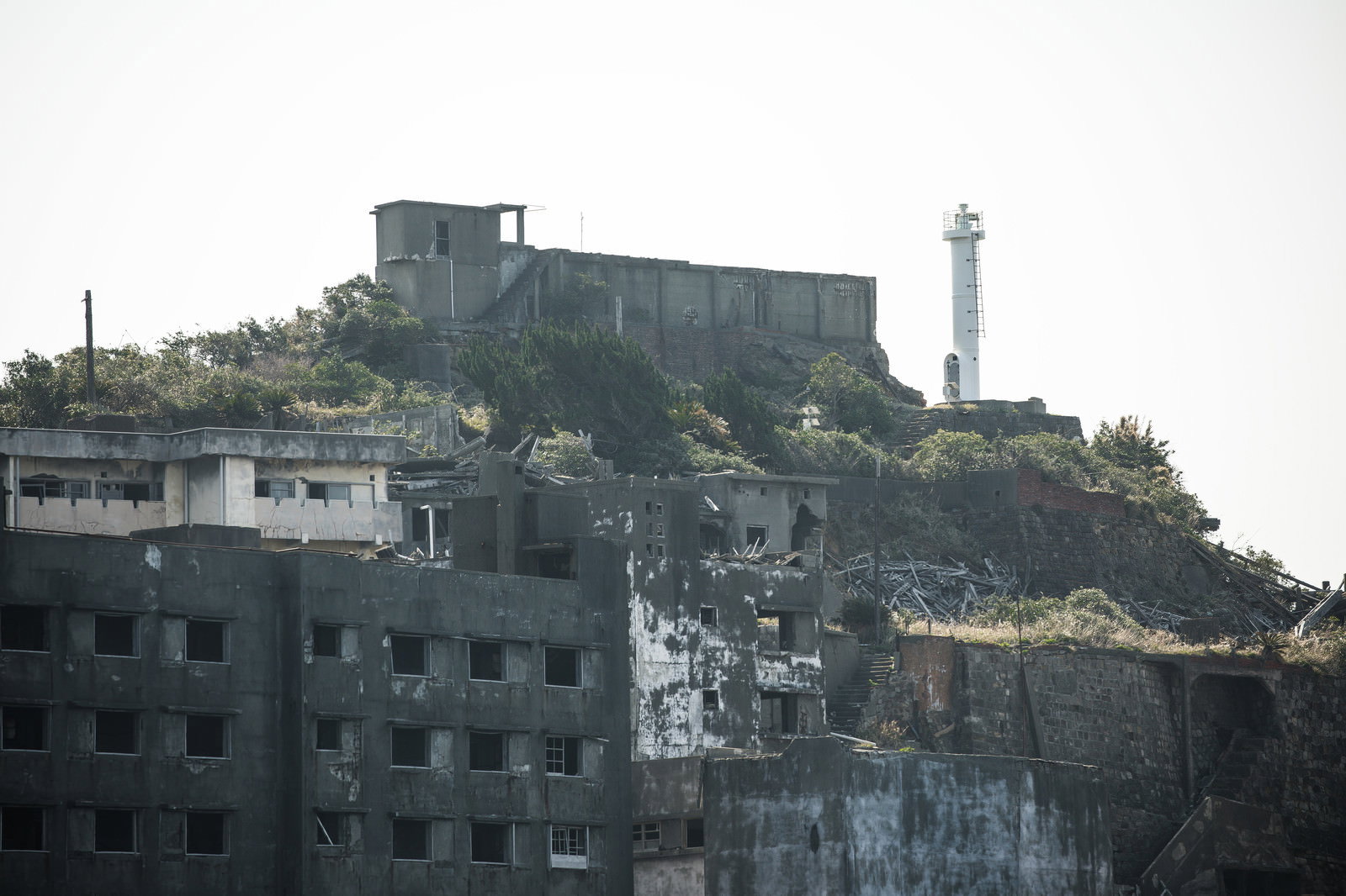 軍艦島の廃墟群の後方にそびえ立つ白いコンクリート造りの肥前端島灯台