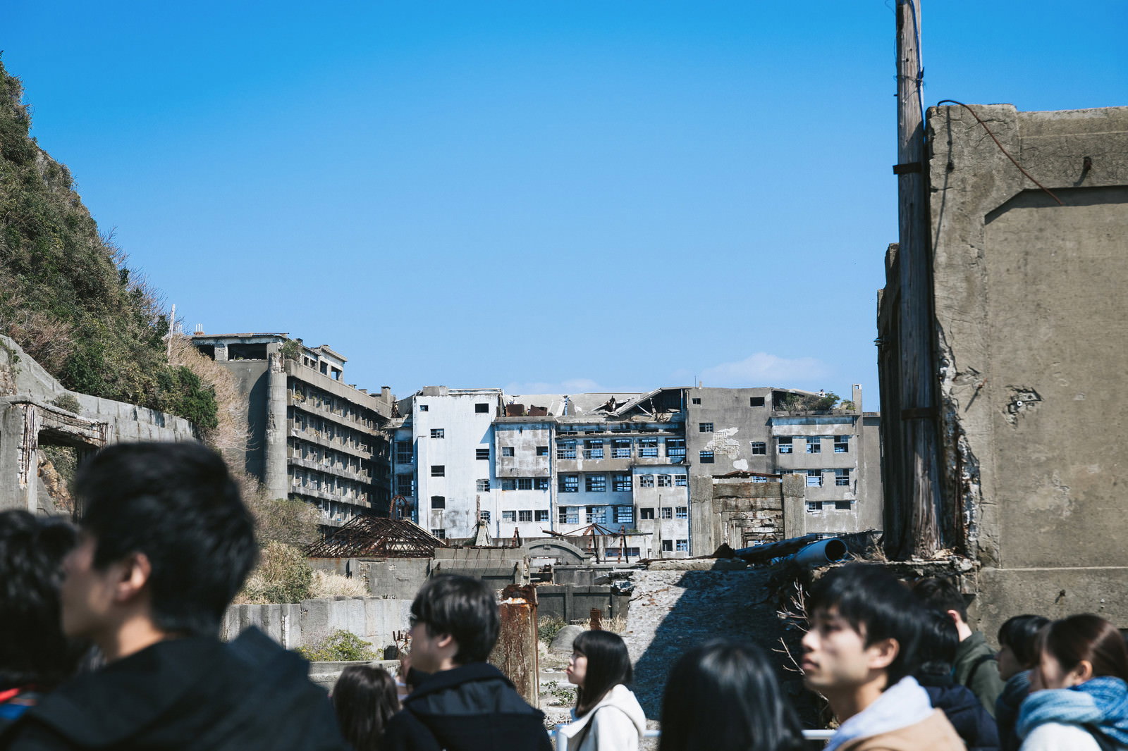 軍艦島の第一見学広場で廃墟の建物群を背景に観光客が見学している風景