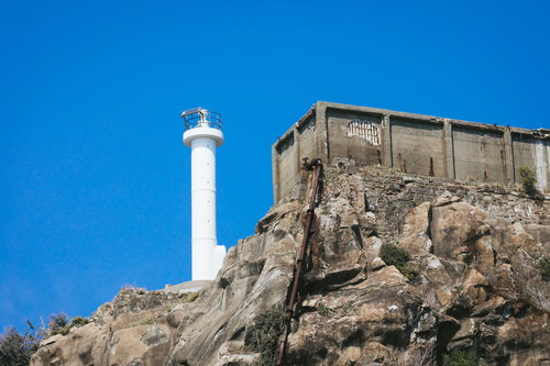 軍艦島の肥前端島灯台と貯水槽が並ぶ岩場と建造物群
