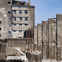 軍艦島の遠景に見える70号棟小中学校跡と貯炭場の写真