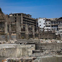 貯炭場越しに見える端島保育園跡と70号棟小中学校跡（軍艦島）の写真