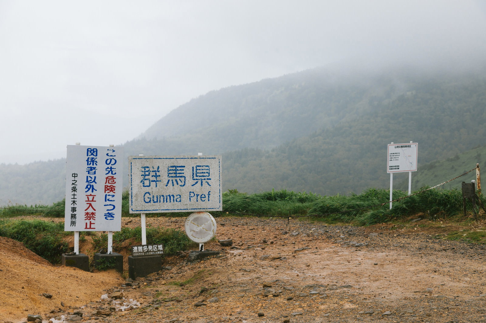 豪雨と霧の中の毛無峠で立入禁止や遭難注意の看板が複数立つ様子