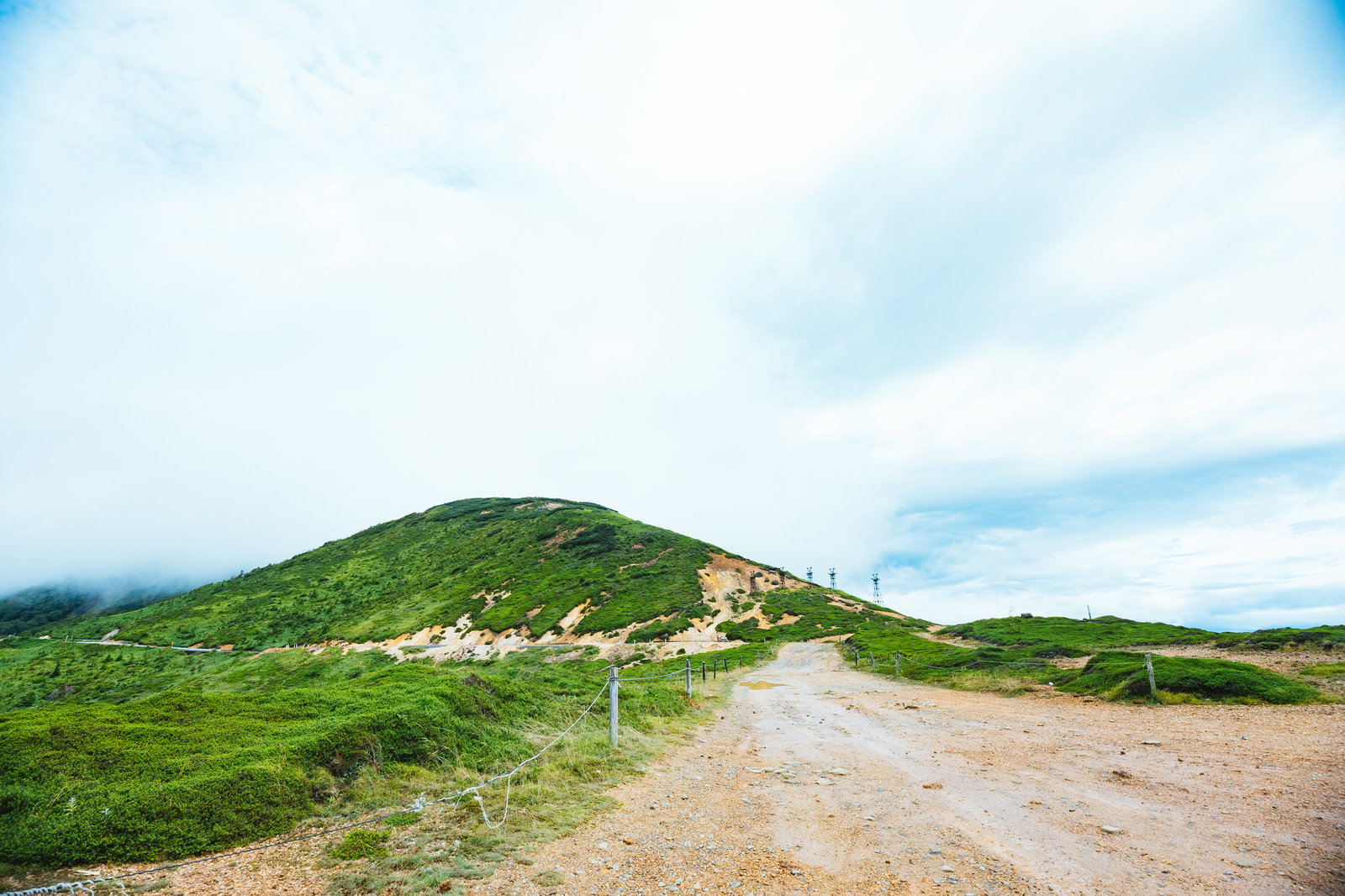 毛無峠の山頂から鉄塔方向を見た風景、緑の山稜と青空が広がる