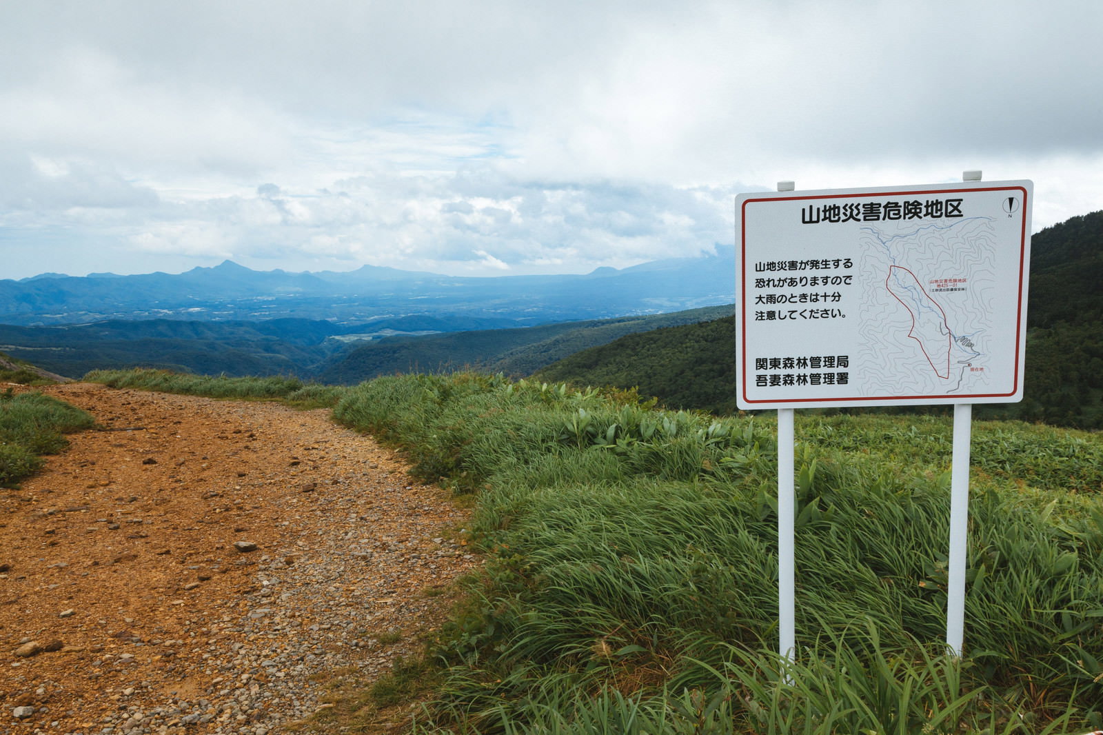 毛無峠に設置された山地災害注意の看板と山岳風景