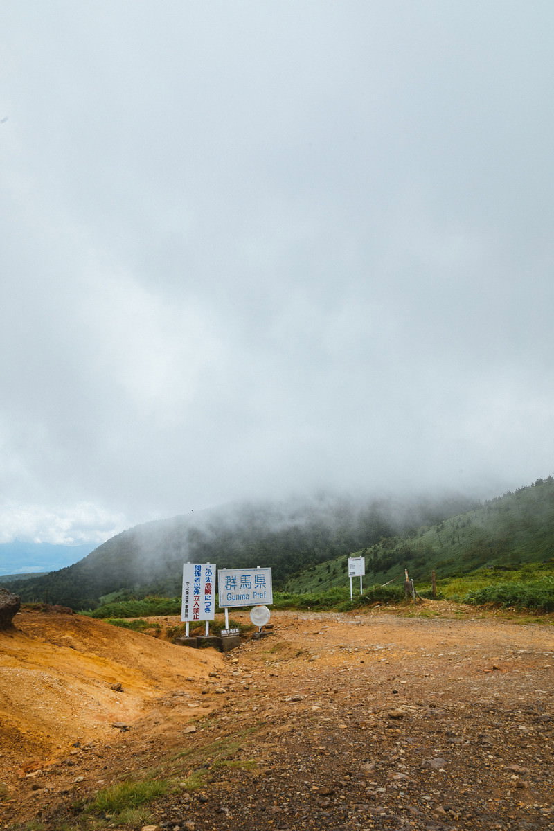 霧に包まれた毛無峠の荒涼とした風景と立入禁止の看板