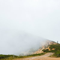 霧に煙る毛無峠の鉄塔跡と苔むした岩の写真