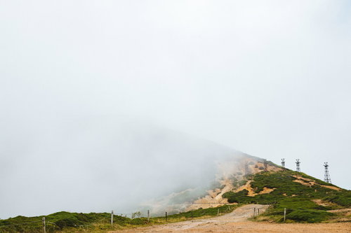 霧に煙る毛無峠の鉄塔跡と苔むした岩