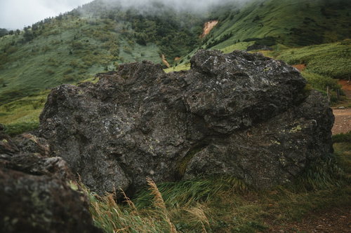 毛無峠の緑の草原に点在する大きな岩石と山々の風景