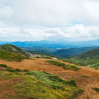 毛無峠の山頂から眺める広大な山岳景観と草原パノラマの写真