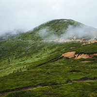 強い風が吹く毛無峠の山肌、霧と雲に覆われた悪天候時の山岳環境の写真