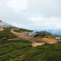 毛無峠の頂上付近駐車場に停まる車両と山間部の景観の写真