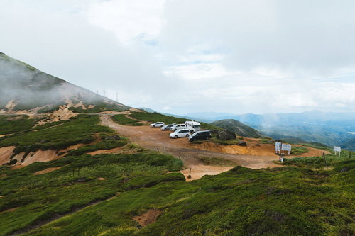 毛無峠の頂上付近駐車場に停まる車両と山間部の景観