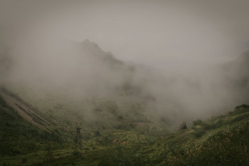 毛無峠の深い霧に包まれた古びた鉄塔と山々の風景