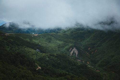 強風が吹き抜ける毛無峠の霧立ちこむ渓谷と山道の景観