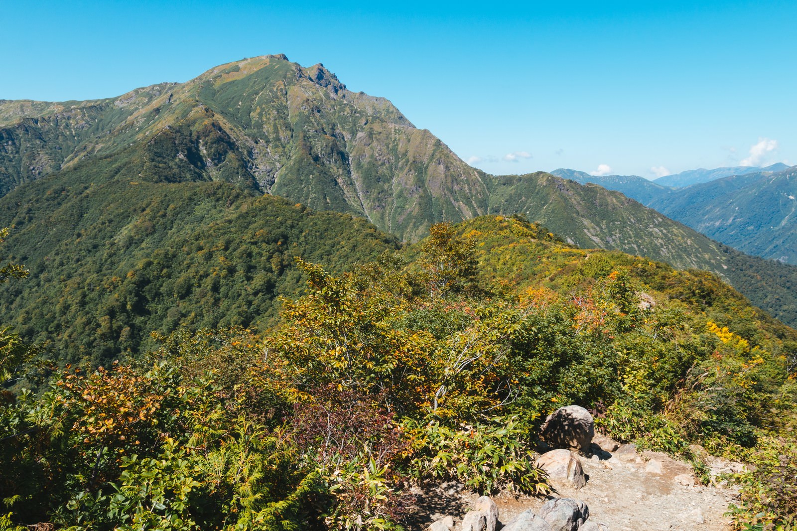 秋の谷川岳の山頂と紅葉に染まった山並みを青空の下で撮影した風景
