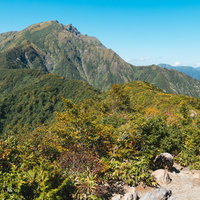 秋の谷川岳と紅葉に染まった山並み、澄んだ青空と登山道の眺望の写真