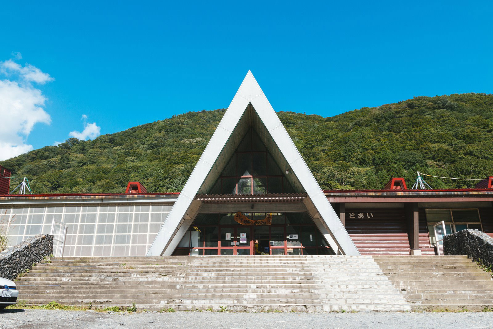 土合駅の白い三角屋根が特徴的な駅舎建物と背景の緑の山々