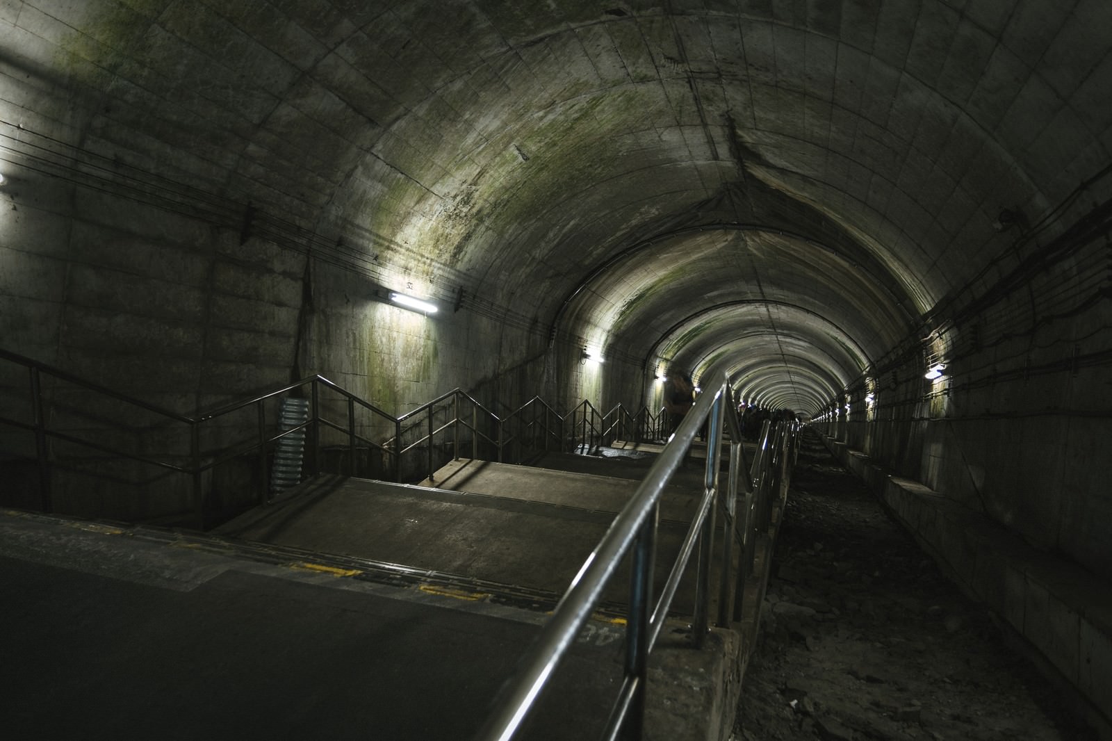 薄暗い地下駅のコンクリート製階段とトンネル構造