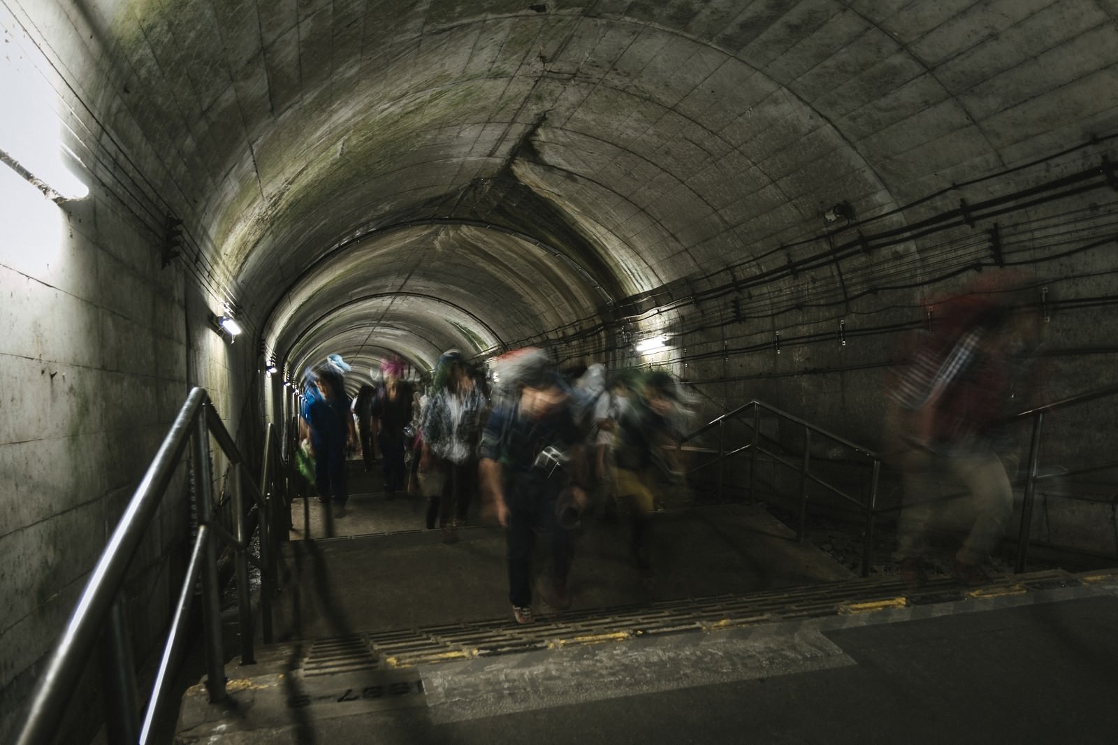 土合駅の薄暗いコンクリート製トンネル階段を歩く人々