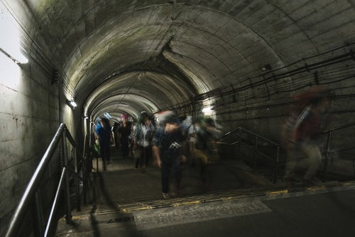 土合駅の薄暗いトンネル階段をのぼる人たち