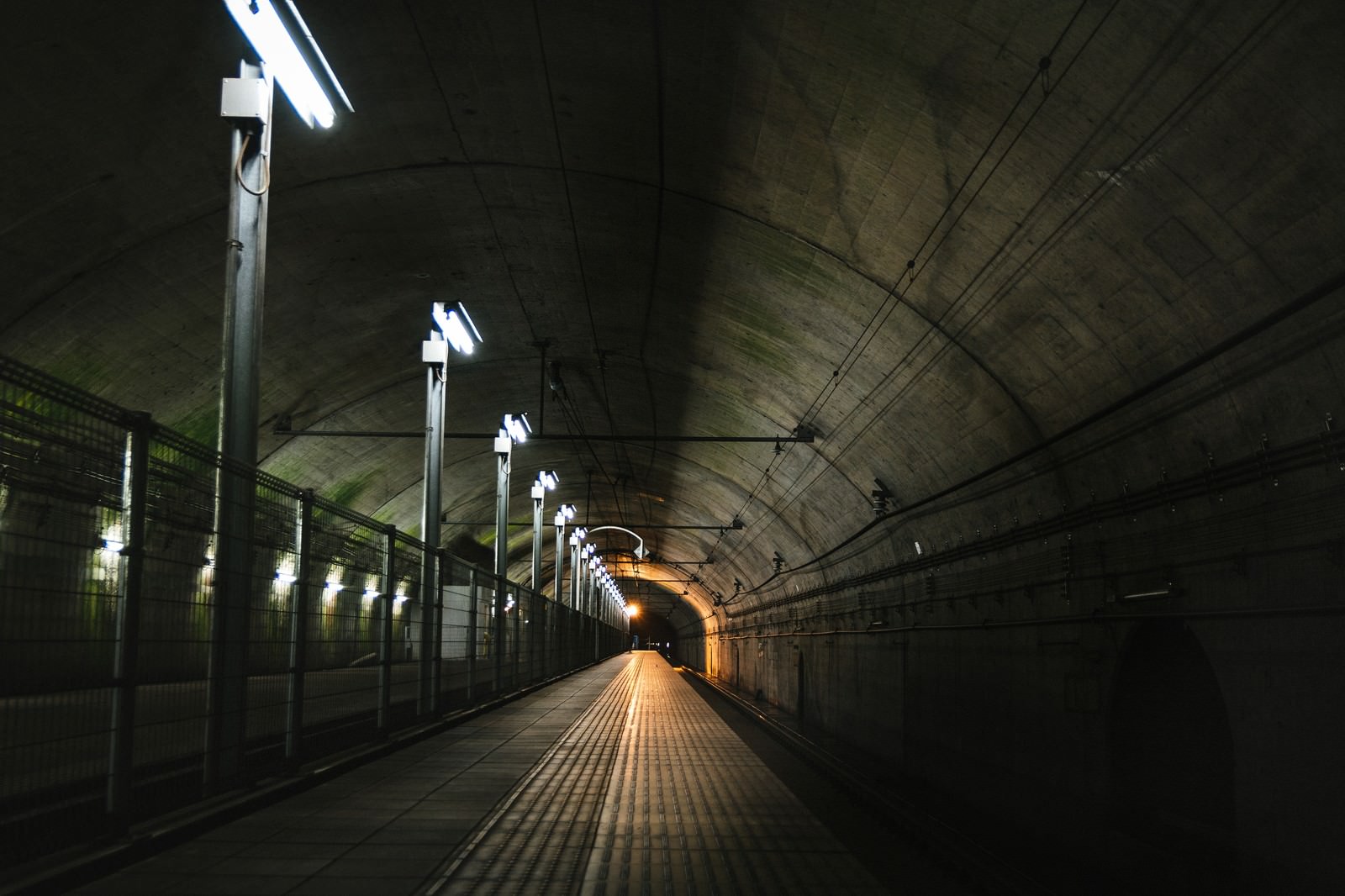 薄暗い照明に照らされた地下駅の長い通路とホーム